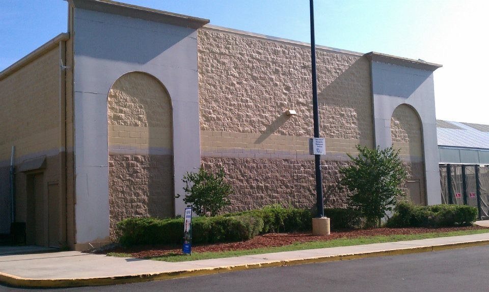 Completed commercial exterior with stone-clad columns, arched openings, and finished landscaping
