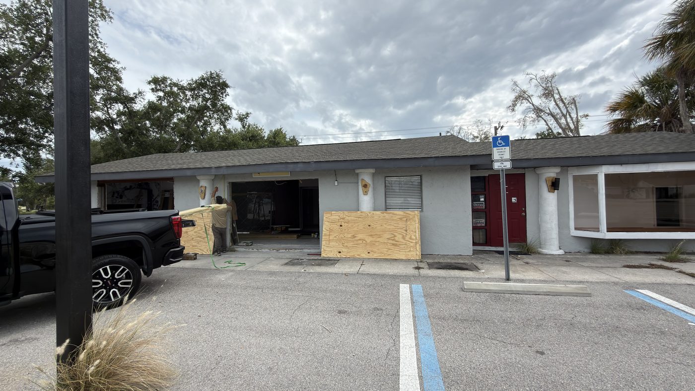 Commercial building before renovation, with boarded windows and damaged exterior