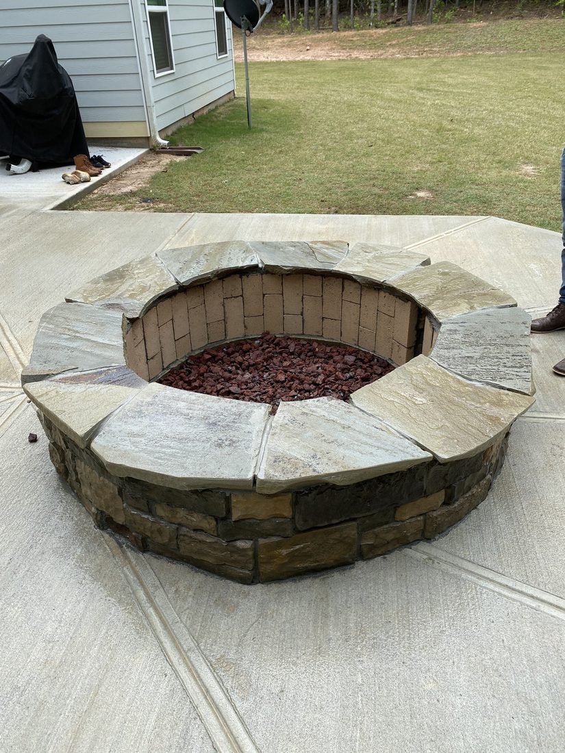Stone fire pit with integrated seating on a concrete patio