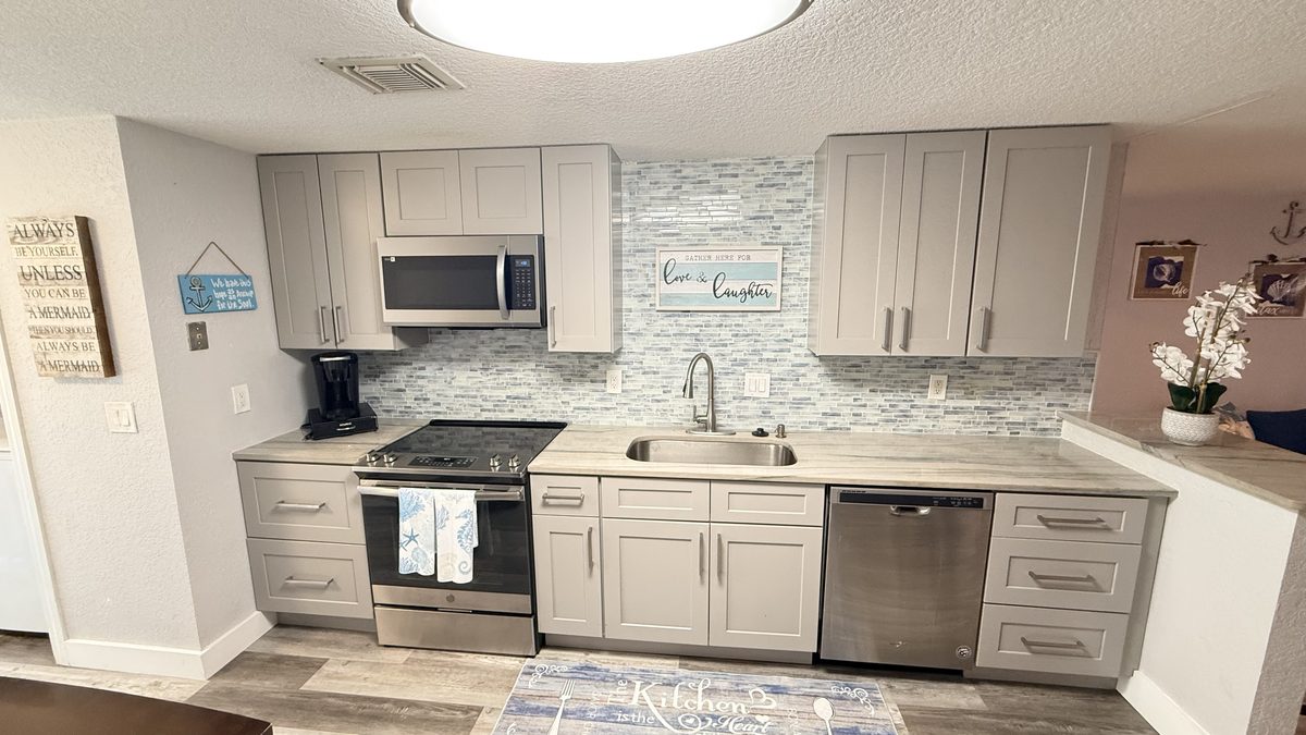 Remodeled kitchen with grey shaker cabinets and mosaic tile backsplash